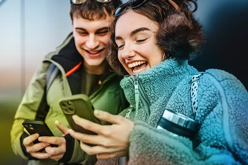 Young man and woman smiling and holding mobile phones